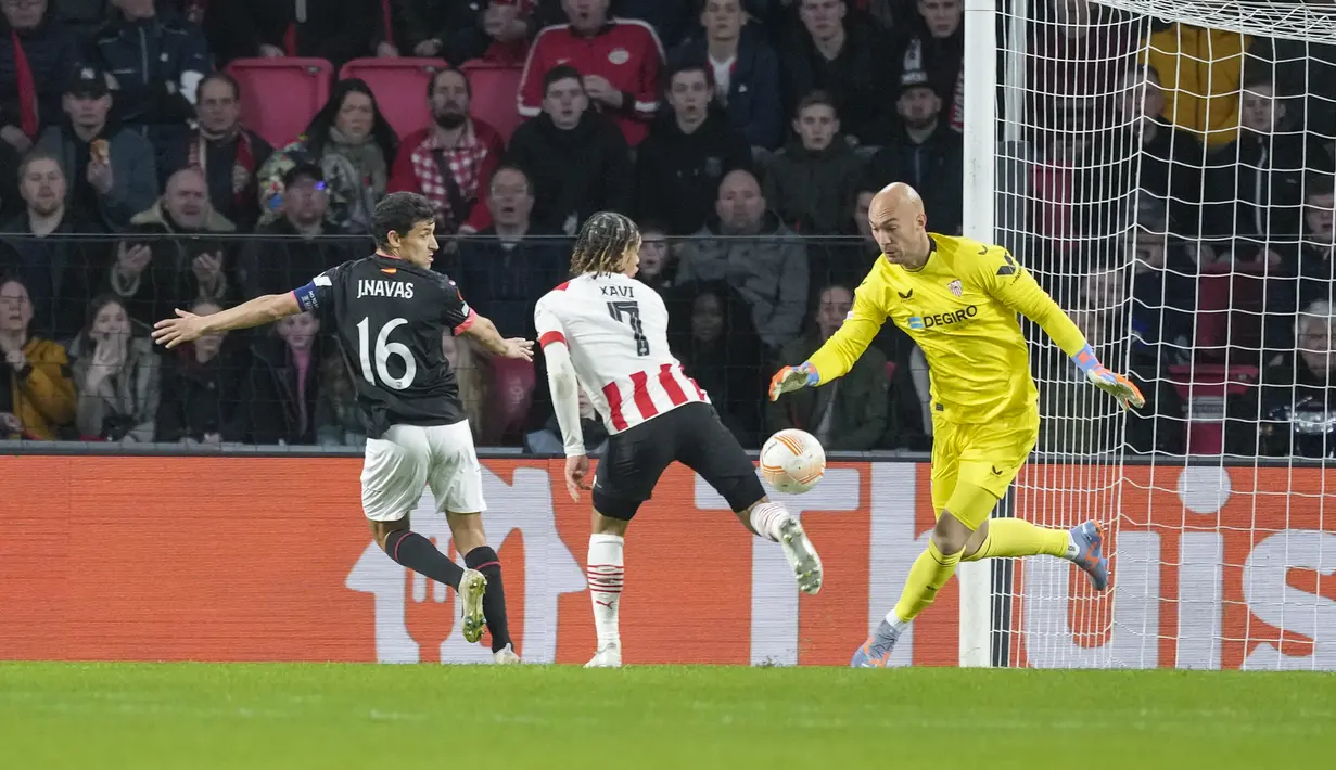 <p>Kiper Sevilla, Marko Dmitrovic berhasil mengamankan bola dari ancaman pemain PSV, Xavi Simons dalam laga leg kedua babak playoff fase gugur Liga Europa 2022/2023 di Philips Stadium, Eindhoven, Jumat (24/2/2023). (AP Photo/Peter Dejong)</p>