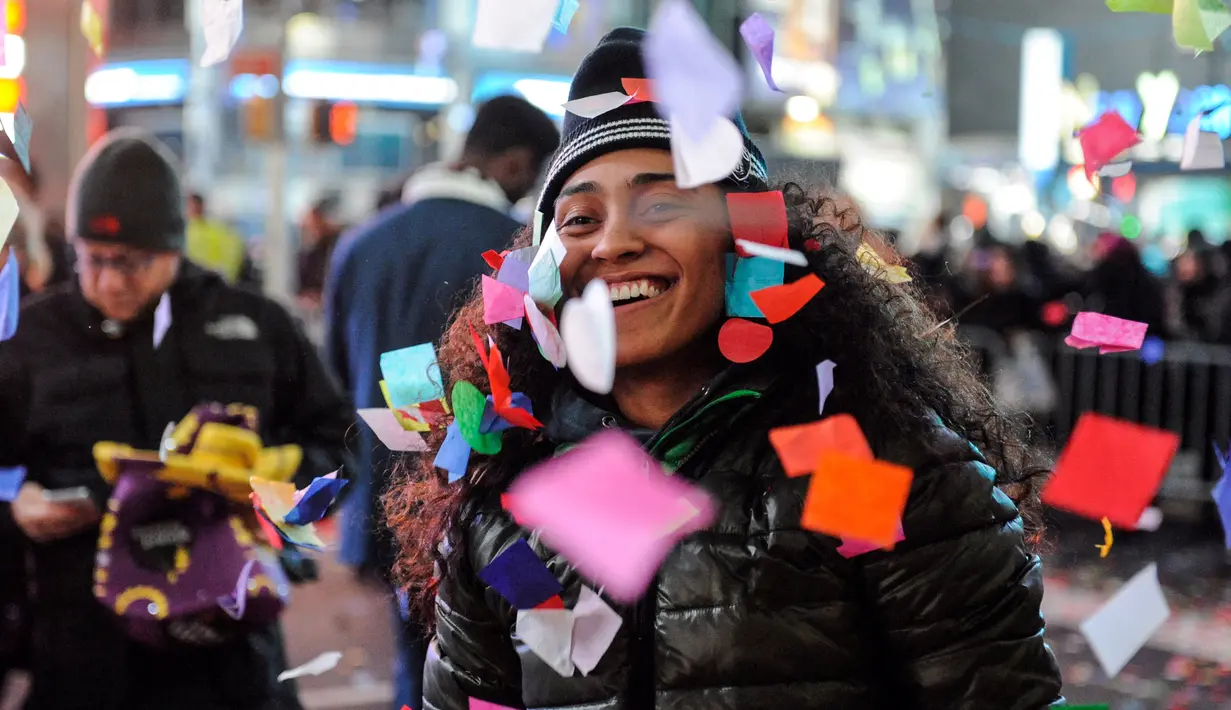 Seorang wanita tersenyum ceria saat bermain confetti dalam perayaan tahun baru di Times Square, New York, AS (1/1). (Reuters/Stephanie Keith)