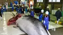 Pekerja menuangkan sake ketubuh Paus Minke yang ditangkap di Kushiro, Hokkaido, Jepang (1/7/2019). Keputusan perburuan Paus Minke tersebut mengundang kecaman dari para aktivis dan negara-negara antiperburuan paus. (AFP Photo/Kazuhiro Nogi)