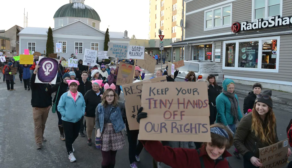Peserta aksi dalam Women's March berjalan di jalan kawasan Washington, AS, Sabtu (21/1). Aksi ini merupakan aksi protes yang menolak Trump karena kebencian dan rasisme yang selama ini sering dilayangkannya. (AP Photo)