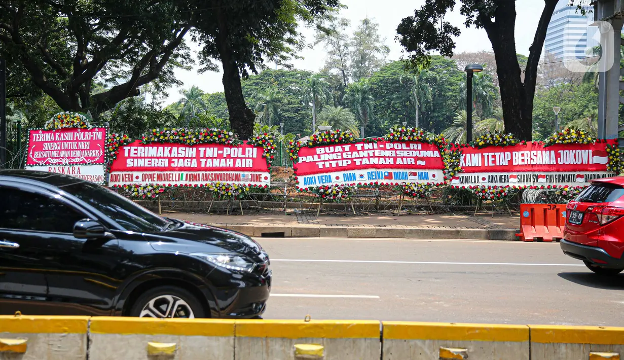 Kendaraan melintasi karangan bunga yang menghiasi kawasan Patung Kuda, Jakarta, Kamis (15/10/2020). Karangan bunga tersebut merupakan apresiasi masyarakat kepada TNI-Polri yang telah menjaga keamanan saat demo. (Liputan6.com/Faizal Fanani)