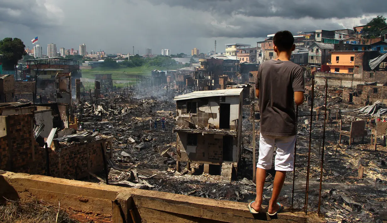 Seorang pria melihat sisa-sisa rumah yang hangus di lingkungan Educandos di Manaus, Brasil (17/12). Kebakaran diduga disebabkan oleh ledakan panci presto yang menghanguskan ratusan rumah warga. (AP Photo/Edmar Barros)
