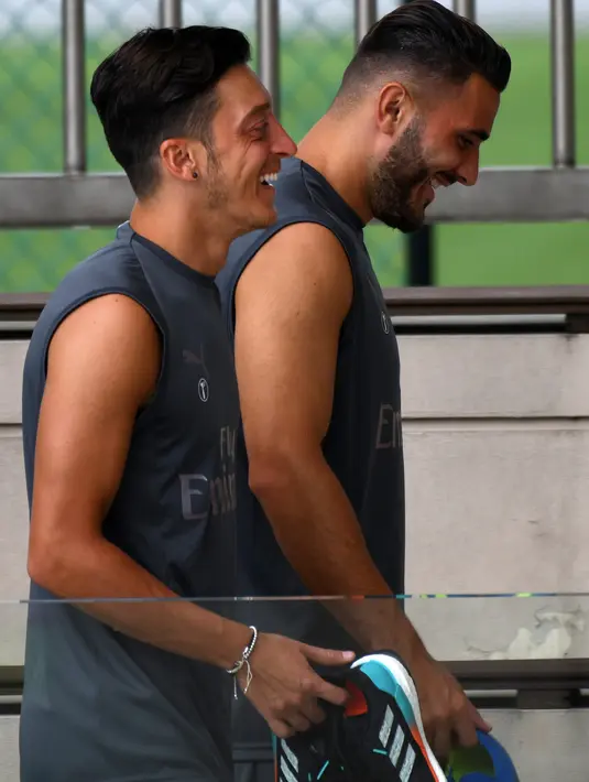 Pemain Arsenal, Mesut Ozil (kiri) berbincang dengan rekan setimnya, Sead Kolasinac saat tiba untuk menjalani sesi latihan untuk kompetisi pramusim International Champions Cup (ICC) 2018 di Singapura, Rabu (27/5). (AFP/Roslan RAHMAN)