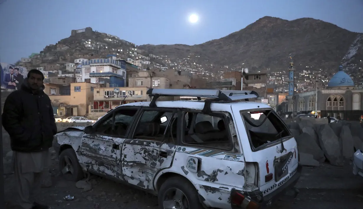 Seorang pria memeriksa kondisi mobil yang rusak usai ledakan bom di Kabul, Afganistan (28/12/2020). Sebanyak 4 orang tewas akibat ledakan yang terjadi di dua tempat terpisah tersebut. (AP Photo/Rahmat Gul)
