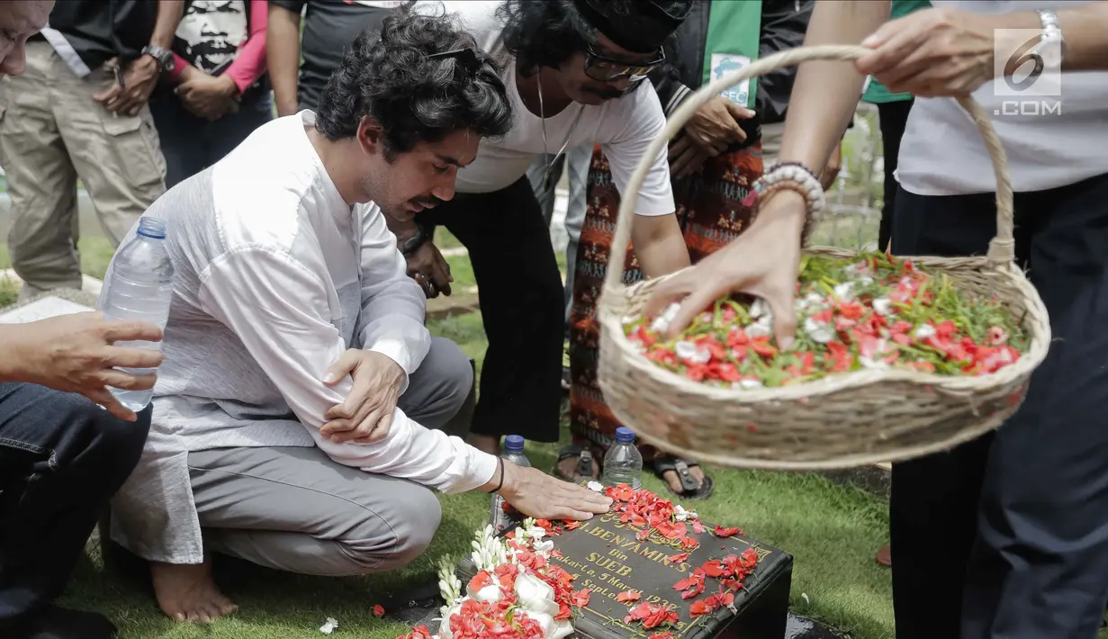 Aktor Reza Rahadian menaburkan bunga di makam Benyamin Sueb di Karet Bivak, Jakarta, Jumat (26/1). Ziarah tersebut ditemani anak ketiga almarhum, H. Beni dan para fans, Benyamin Sueb Fans Club. (Liputan6.com/Faizal Fanani)