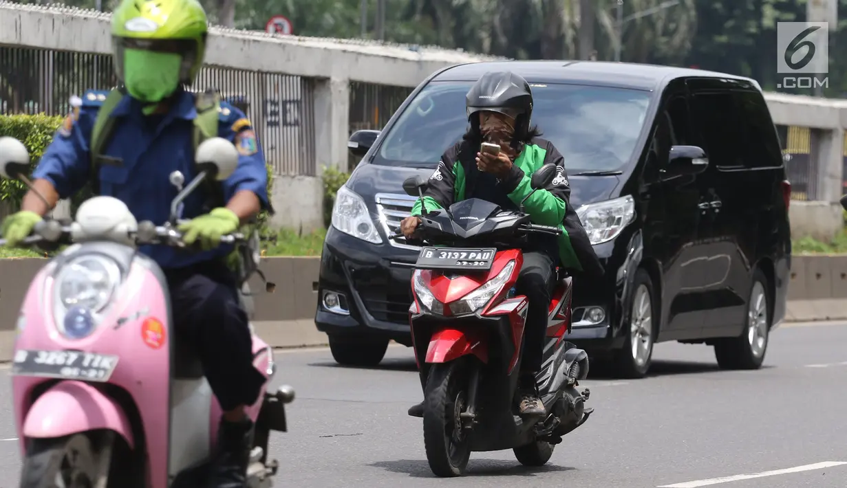Pengemudi ojek online mengoperasikan telepon seluler sambil mengendarai sepeda motor di Jalan Gatot Subroto, Jakarta, Kamis (8/3). Menggunakan telepon seluler saat berkendara tergolong berpotensi mengganggu konsentrasi. (Liputan6.com/Arya Manggala)