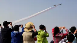 Pengunjung mengambil gambar jet tempur yang sedang beraksi di acara Zhuhai Air Show, di Provinsi Guangdong, Tiongkok, Selasa (1/11). Pertunjukan udara ini merupakan upaya Tiongkok untuk memodernisasi kemampuan militernya. (REUTERS/ China Daily)