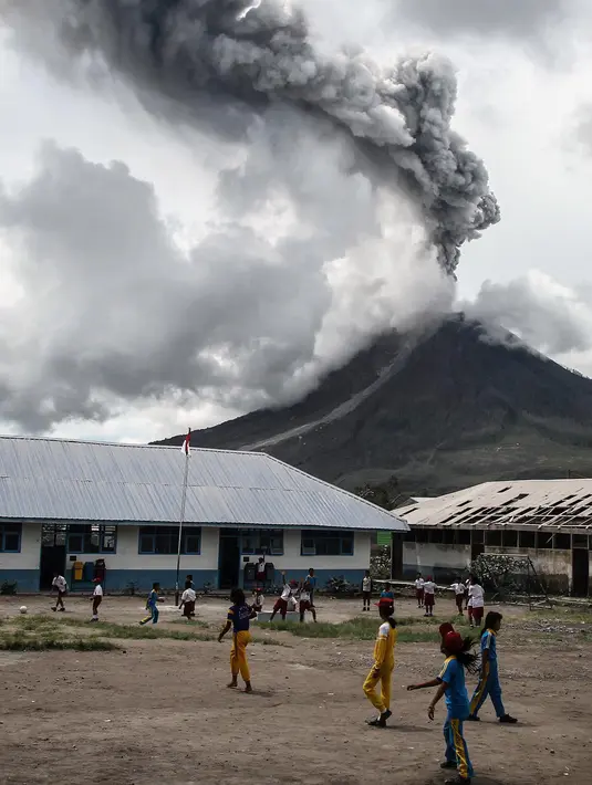Sejumlah murid SD bermain di sekolah mereka saat erupsi Gunung Sinabung di Karo, Sumatera Barat (13/11). Meski erupsi, aktivitas kegiatan belajar di sekolah di Kabupaten Karo tersebut berjalan seperti biasa. (AFP Photo/Ivan Damanik)