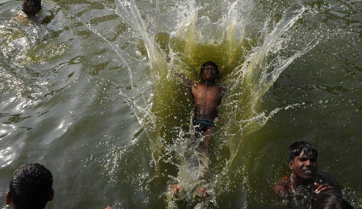 Cuaca yang panas dimanfaatkan oleh sejumlah warga di India untuk mandi di sungai, India, Rabu (5/4). Meski air sungai telah tercemar tidak menghalangi mereka untuk tetap mandi di sungai tersebut. (AFP PHOTO / ARUN SANKAR)