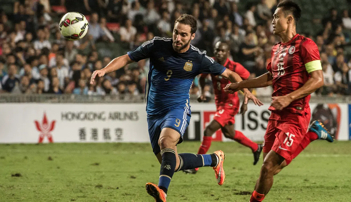 Striker Argentina, Gonzalo Higuain (kiri) menguasai bola dibayangi bek Timnas Hong Kong, Wai Ho Chan pada laga persahabatan internasional di Hong Kong Stadium, Hong Kong (14/10/2014). (AFP/Anthony Wallace)