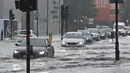 Mobil melintasi jalan yang banjir saat hujan lebat di distrik The Nine Elms London (25/7/2021). Banjir parah terjadi di Ibu Kota Inggris London yang menyebabkan lumpuhnya sejumlah area di kota tersebut. (AFP/Justin Tallis)