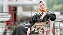 Coba lihat, outfit yang dipakai Angel ini cukup glamor bukan? Long dress hitam dengan motif bunga-bunga ini juga terdapat aksen rempel di bagian dadanya. Makin terlihat mewah dengan hijab berwarna oranye. (Instagram/angellelga)