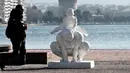Seorang pria berjalan di samping patung karya seniman China Xu Hongfei di Thessaloniki, Yunani, Rabu (19/12). Sebanyak 15 patung karya Xu Hongfei menghiasi tepi pantai Thessaloniki. (Sakis Mitrolidis/AFP)