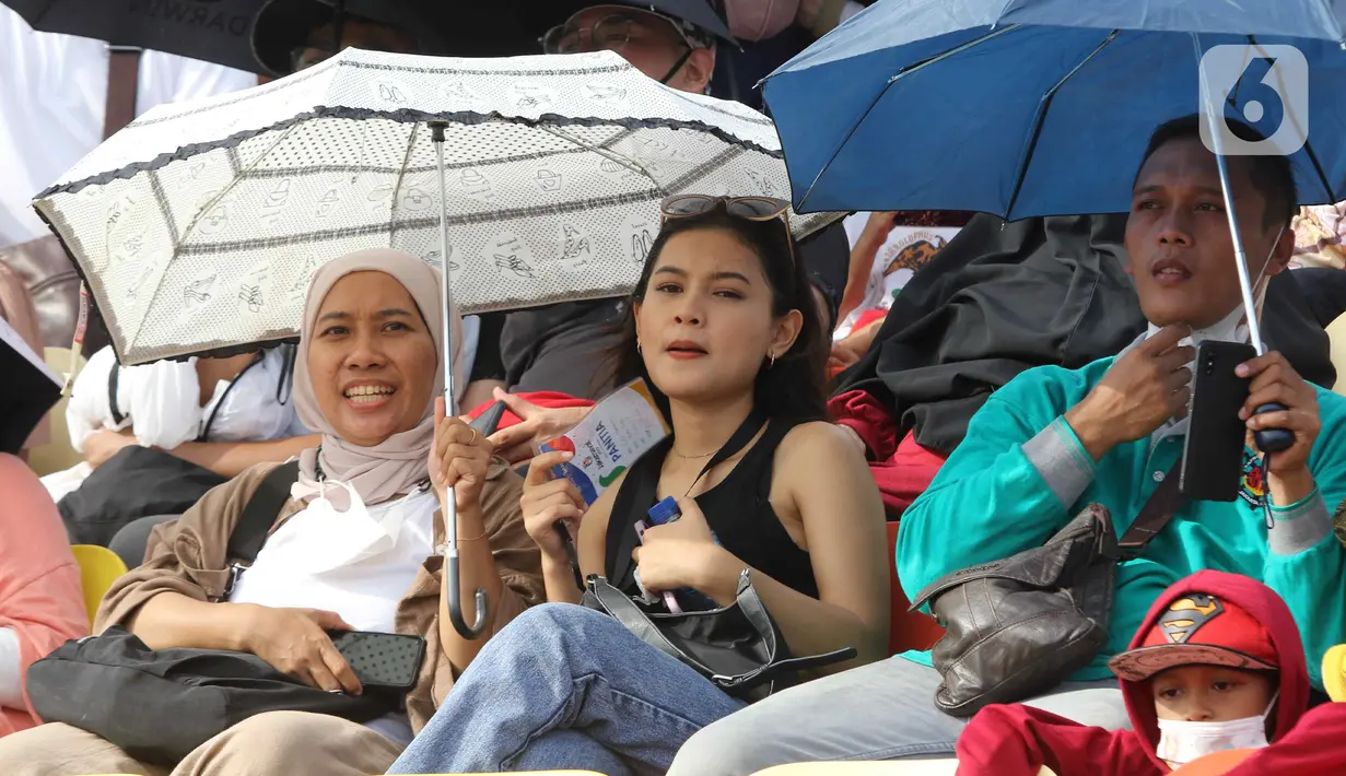 Penonton menyaksikan parade dalam pagelaran Jakarnaval 2022 di Jakarta International Eprix Circuit, Ancol, Minggu (14/8/2022). Gelaran Jakarnaval 2022 yang mengangkat tema "Kekayaan Intelektual Nusantara untuk Dunia" tersebut menampilkan parade komunitas pegiat seni budaya, marching band, dan kendaraan hias. (Liputan6.com/Herman Zakharia)