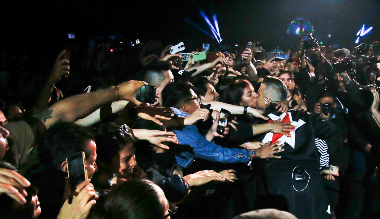 Penyanyi asal Inggris Robbie Williams mencium seorang fans saat tampil selama Festival Musik Corona Capital di Meksiko (17/11). (AP Photo/Eduardo Verdugo)