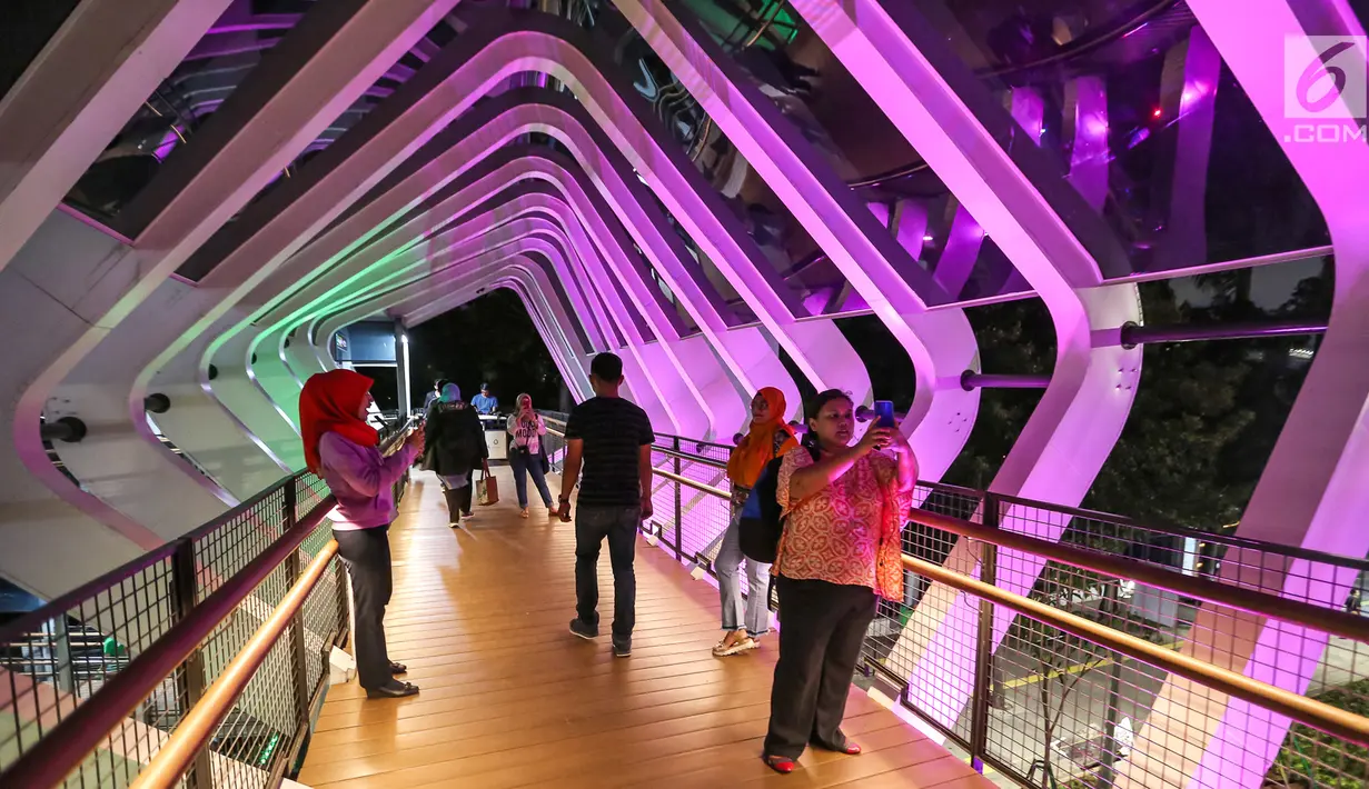 Sejumlah pejalan kaki mengabadikan Jembatan Penyeberangan Orang (JPO) Gelora Bung Karno lewat foto di Jalan Jend Sudirman, Jakarta, Senin (4/3) malam. JPO tersebut baru saja diresmikan Gubernur DKI Jakarta Anies Baswedan. (Liputan6.com/Fery Pradolo)