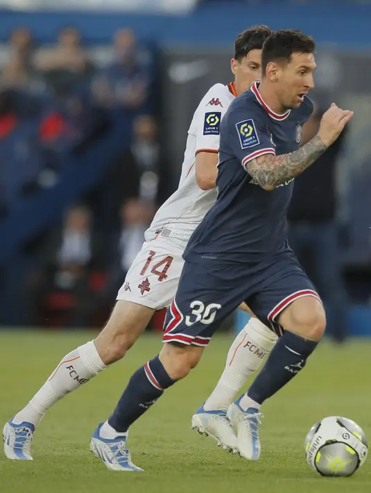 <p>Penyerang PSG, Lionel Messi membawa bola dari kejaran pemain Metz, Vincent Pajot pada pertandingan lanjutan Liga 1 Prancis di stadion Parc des Princes di Paris, Prancis, Minggu (22/5/2022). PSG pesta lima gol ke gawang Metz. (AP Photo/Michel Spingler)</p>