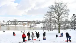 Warga menikmati permainan kereta luncur di taman Dunorlan di Tunbridge Wells (27/2). Cuaca ekstrem yang melanda sebagian wilayah Eropa menyebabkan warga dan wisatawan mengalami sakit dan beberapa meninggal akibat kedinginan. (AFP Photo/Ben Stansall)