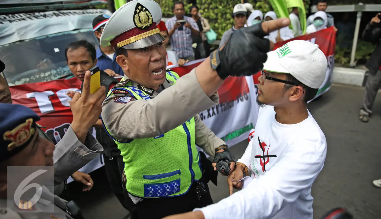 Aparat bersitegang dengan massa aksi dari Front Pancasila saat berusaha masuk menuju Hotel Aryaduta, Jakarta, Senin (18/4). Mereka menolak Simposium PKI yang dapat dimanfaatkan menghidupkan kembali paham komunis. (Liputan6.com/Faizal Fanani)