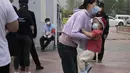 <p>Seorang wanita menggendong seorang anak di dekat garis selama pengujian massal untuk COVID-19 di distrik Chaoyang, Bejing, Senin (25/4/2022). Ibu kota China, Beijing, mulai menguji jutaan penduduk dan menutup kawasan perumahan dan bisnis pada Senin di tengah wabah baru COVID-19. (AP Photo/Ng Han Guan)</p>