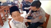 Salah seorang pelajar di Tasikmalaya tengah mendapatkan vaksinasi dari seorang petugas Polres Tasikmalaya. (Liputan6.com/Jayadi Supriadin)