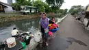 Seorang wanita membawa pakaiannya usai di cuci di aliran Kali Maja, Jakarta, Selasa (7/11). Air Kali Maja yang yang kotor dan tidak layak, terpaksa dimanfaatkan untuk memenuhi kebutuhannya terutama mencuci pakaian. (Liputan6.com/JohanTallo)