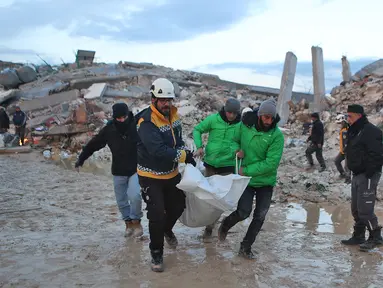 Penyelamat Suriah membawa jenazah melewati bangunan yang runtuh saat operasi pencarian berlanjut setelah gempa mematikan di kota Sarmada, di provinsi Idlib barat laut yang dikuasai pemberontak Suriah pada 6 Februari 2023. Setidaknya 1.400 orang tewas dan 3.411 terluka di seluruh Suriah hari ini dalam gempa bumi yang berpusat di Turki barat daya, kata pemerintah dan penyelamat. (AFP/Aaref Watad)