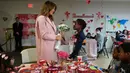 Melania Trump menerima buket bunga dari Amani (13) asal Kenya dalam kunjungannya di rumah sakit National Institutes of Health, Maryland, Kamis (14/2). Melania Trump menghabiskan momen Hari Valentine bersama anak-anak di rumah sakit.  (AP/Susan Walsh)