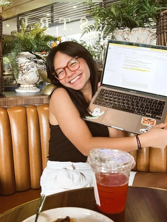 Amel Carla tersenyum lebar saat berada di sebuah cafe menunjukan tugas yang sedang ia kerjakan. Artis multitalenta ini juga memiliki prestasi akademik yang tidak kalah dengan bakatnya di dunia entertainment. (Instagram/@amelcarla)