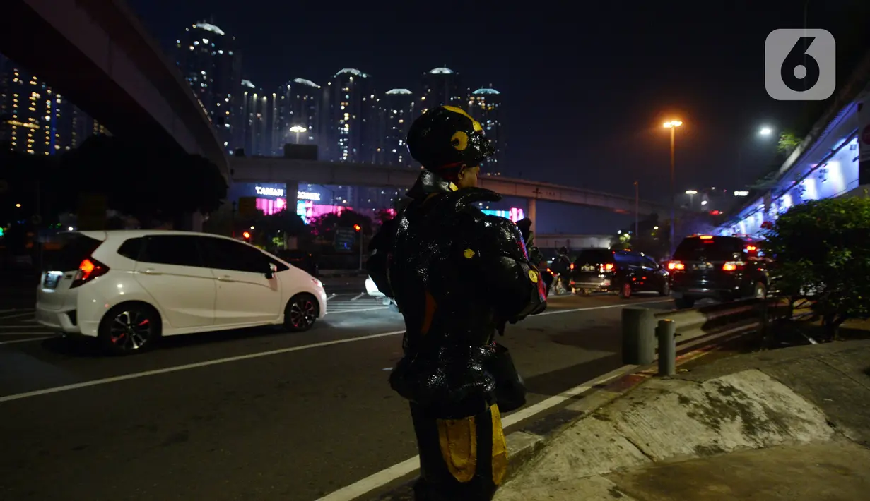 Seorang robot saat menghibur pengendara di kawasan Tomang, Jakarta, Selasa (14/9/2021). Abi (20) dan Nujum (48) mengenakan kostum robot Iron Man untuk mengais rejeki dan menghibur para pengendara dari kemacetan lalu lintas yang dilakukan sejak pandemi COVID-19. (merdeka.com/Imam Buhori)