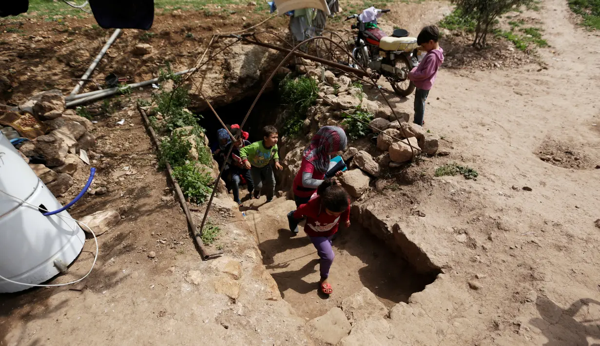Anak-anak pengungsi keluar dari gua usai mengikuti kegiatan belajar di Tramla, Provinsi Idlib, Suriah, pada 27 Maret 2016. Gua ini mampu menampung sekitar 120 siswa yang ingin belajar. (REUTERS/Khalil Ashawi)