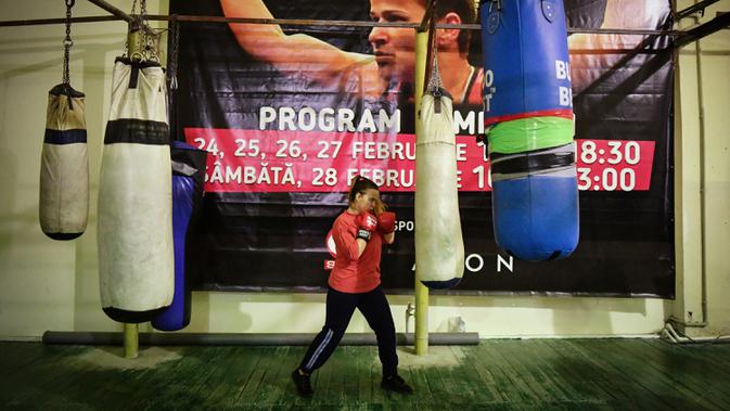 Salah satu gadis Rumania saat berlatih dengan latar belakang spanduk bergambar Steluta Duta di Buzau, Rumania (17/1/2020). Keberhasilan Steluta Duta memberi inspirasi bagi remaja yatim piatu untuk atlet tinju profesional. (AFP/Daniel Mihailescu)