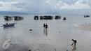 Sepasang wisatawan berjalan menuju kapal penumpang sementara seorang anak (kanan) bermain di pinggir pantai Pulau Bunaken, Manado, Sabtu (17/12). Taman Nasional Bunaken ini memiliki keindahan alam dan biota laut. (Liputan6.com/Fery Pradolo)