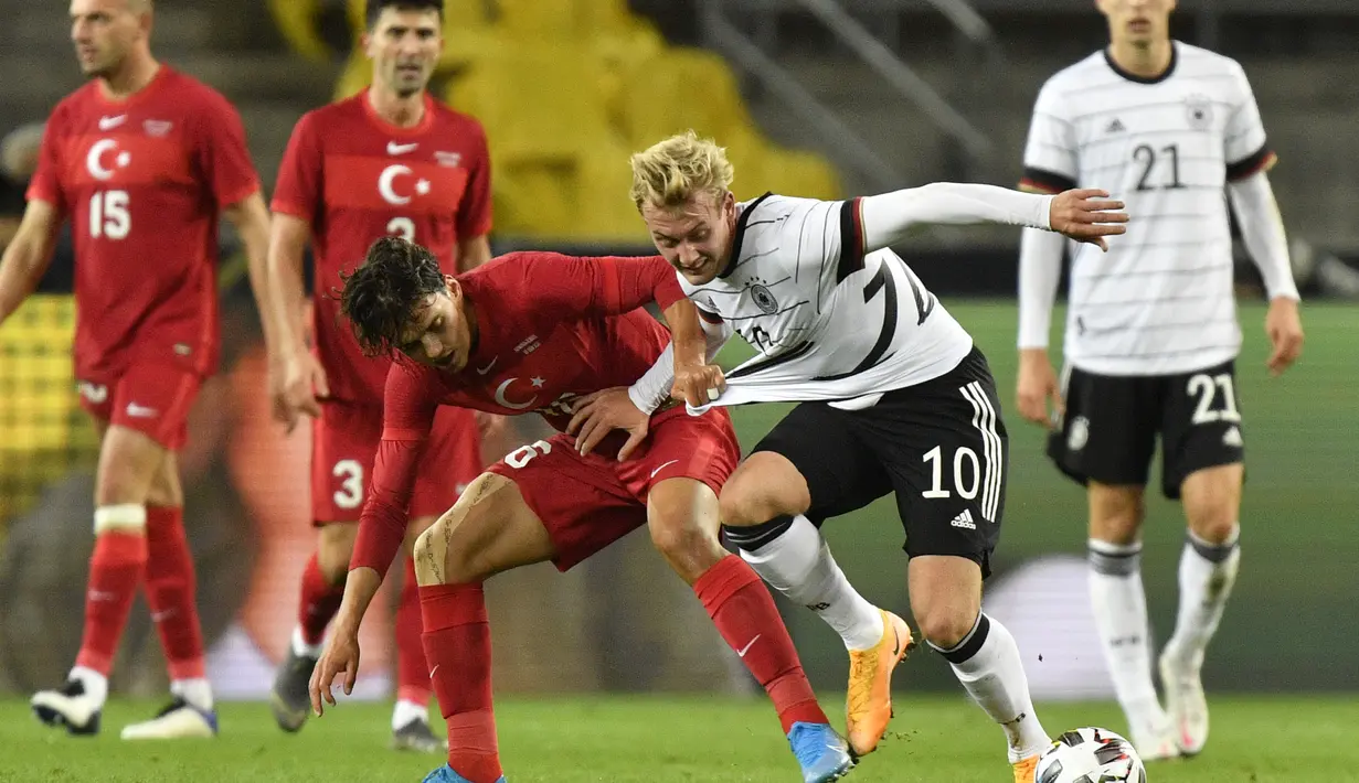Gelandang Jerman, Julian Brandt berebut bola dengan penyerang Turki, Enes Unal pada pertandingan persahabatan di Stadion RheinEnergie, Cologne, Kamis  (8/10/2020). Jerman bermain imbang 3-3 atas Turki. (AP Photo/Martin Meissner)