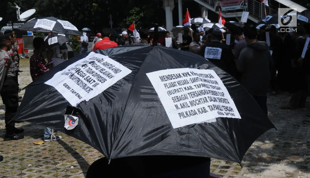 Aktivis dari Gema Tapteng membawa payung hitam saat aksi unjuk rasa di depan gedung KPK, Jakarta (9/5). (Merdeka.com/Dwi Narwoko)