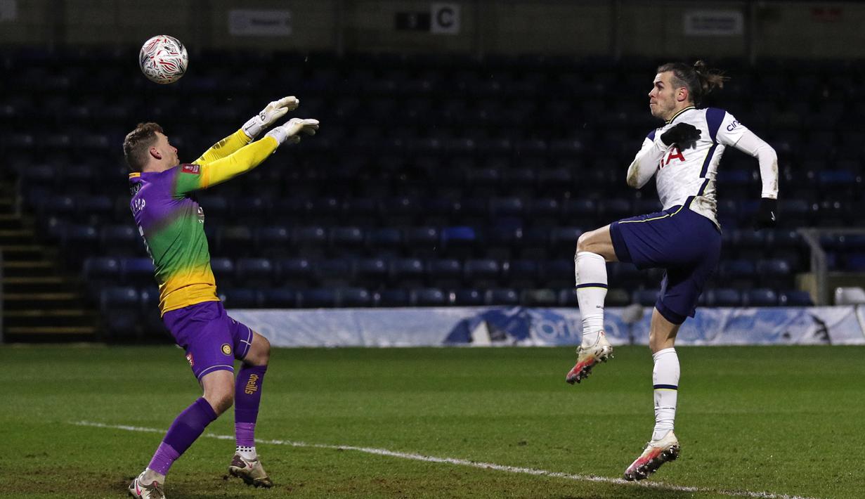 Gelandang Tottenham Hotspur, Gareth Bale mencetak gol penyeimbang 1-1 ke gawang Wycombe Wanderers yang dijaga kiper Ryan Alisop dalam laga babak keempat Piala FA 2020/21 di Adams Park Stadium, Senin (25/1/2021). Tottenham Hotspur menang 4-1 atas Wycombe Wanderers. (AFP/Adrian Dennis)