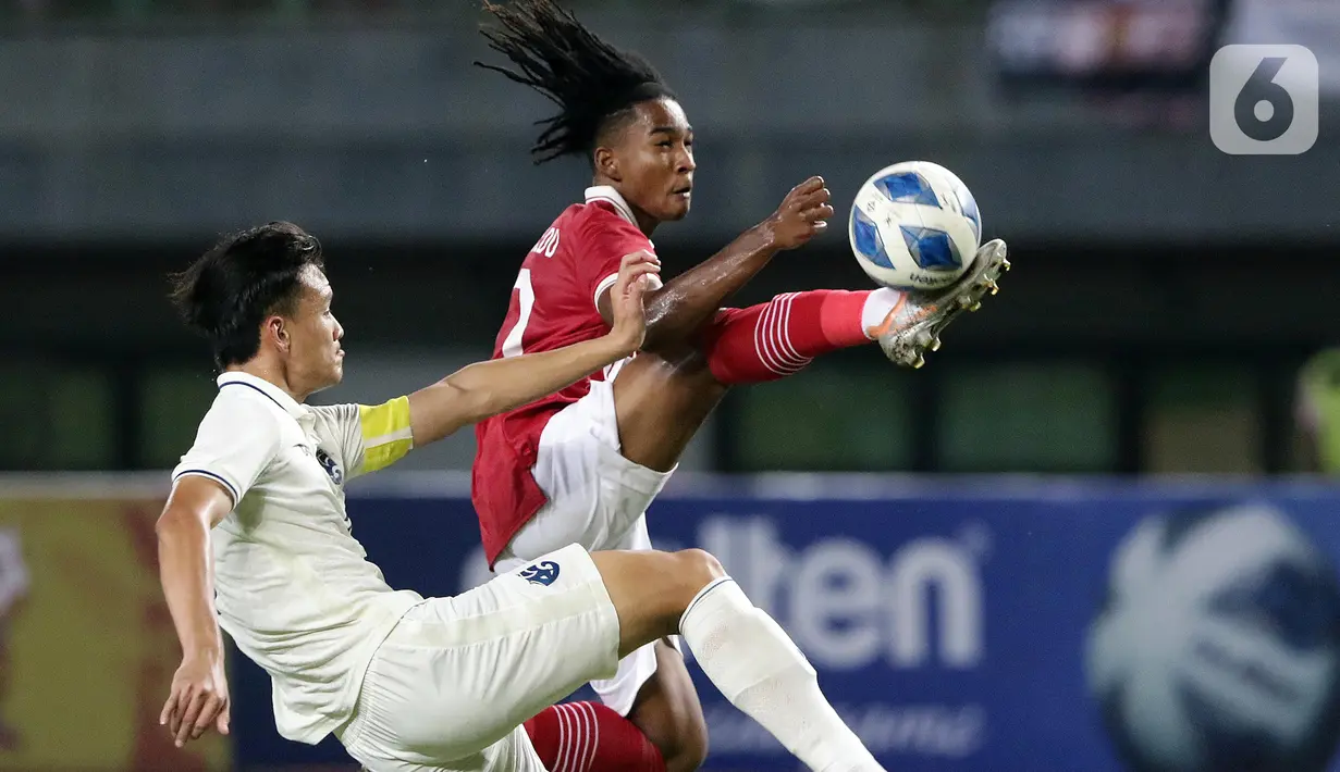 Pemain depan Timnas Indonesia U-19, Ronaldo Kwateh (kanan) berebut bola dengan Chanapach Buaphan (Thailand U-19) pada lanjutan penyisihan grup A Piala AFF U-19 2022 di Stadion Patriot Candrabhaga, Bekasi, Jawa Barat, Rabu (6/7/2022). Kedua tim tampil ngotot dan saling serang dan laga berakhir imbang 0-0. (Liputan6.com/Helmi Fithriansyah)