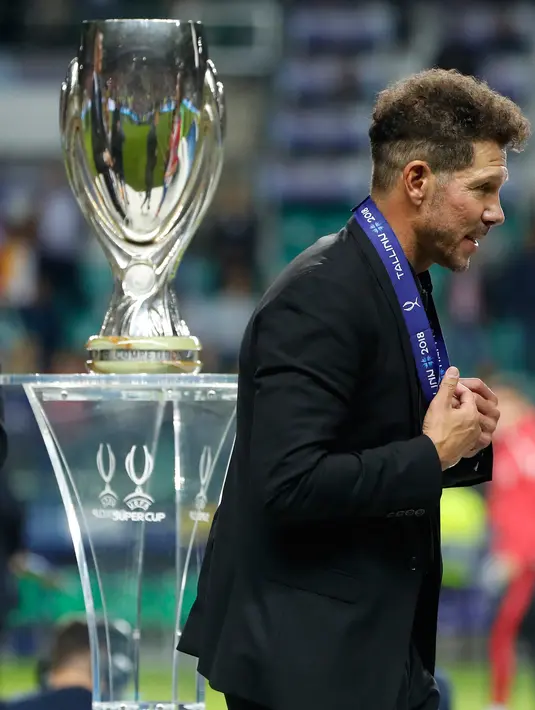 Pelatih Atletico Madrid, Diego Simeone berjalan  melewati trofi iala Super Eropa setelah mengalahkan Real Madrid di Lillekula Stadium di Tallinn, Estonia, (15/8). Atletico Madrid menang 4-2 atas Real Madrid. (AP Photo/Pavel Golovkin)