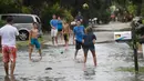 Suasana keluarga Wilkins saat bermain dalam genangan banjir di jalan Pantai Fort Myers, Florida, Senin (31/7). Gubernur Rick Scott mengumumkan keadaan darurat untuk 31 negara bagian Florida selatan dan tengah. (The News-Press via AP/Andrew West)