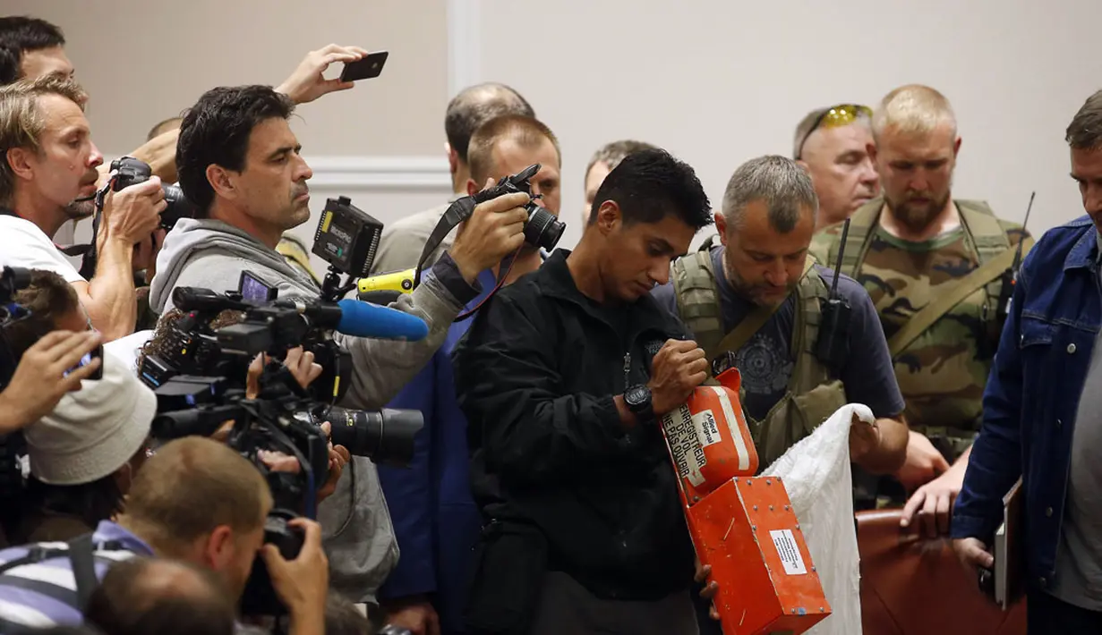 Salah satu tim investigator (tengah) meneliti kotak hitam pesawat Malaysia Airlines MH-17 di Donetsk, (22/7/2014). (REUTERS/Maxim Zmeyev)