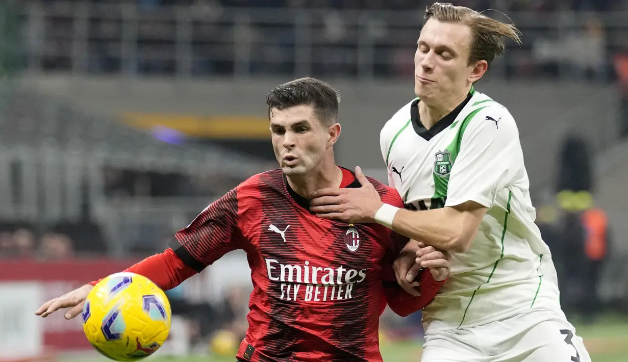 Striker AC Milan, Christian Pulisic (kiri) berebut bola dengan bek Sassuolo, Marcus Pedersen pada laga pekan ke-18 Serie A Liga Italia 2023/2024 di San Siro Stadium, Milan, Sabtu (30/12/2023) malam waktu setempat. (AP Photo/Antonio Calanni)