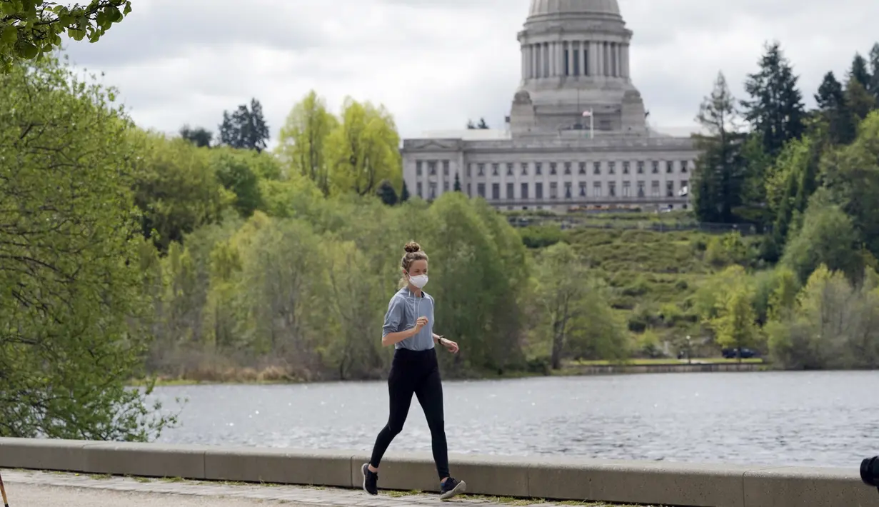 Seseorang memakai masker saat jogging di dekat Capitol di Olympia, Washington, Selasa (27/4/2021). Warga Amerika Serikat (AS) yang telah menerima vaksin COVID-19 tidak lagi diwajibkan mengenakan masker saat berada di luar ruangan jika tidak ada kerumuman. (AP Photo/Ted S. Warren)
