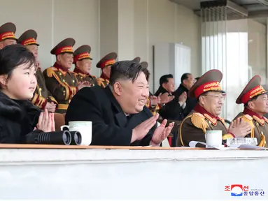 Pemimpin Korea Utara Kim Jong Un dan putrinya Kim Ju-ae bertepuk tangan saat menyaksikan pertandingan sepak bola antara staf Kabinet dan Kementerian Pertahanan Nasional, di Korea Utara pada 17 Februari 2023. Kim Jong Un mengajak putrinya dalam rangka merayakan ulang tahun kakeknya Kim Jong Il menandai penampilan pertama gadis itu yang tidak secara terbuka terkait dengan nuklir. (AFP/KCNA Via KNS)