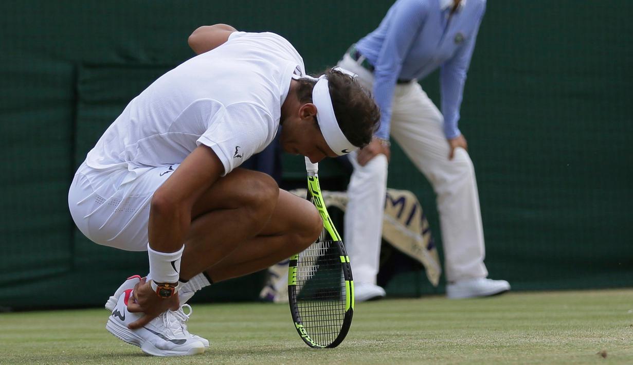 Petenis Spanyol, Rafael Nadal memegang pergelangan kakinya saat melawan petenis asal Luksemburg, Giller Muller pada perempat final Wimbledon 2017 di London, Senin (10/7). Nadal disingkirkan petenis unggulan ke-16 asal Luksemburg. (AP Photo/Tim Ireland)