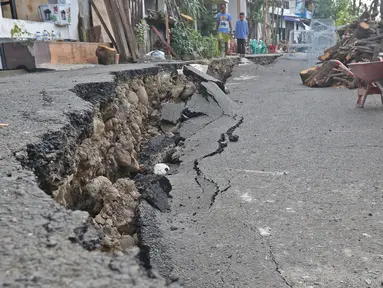 Warga melintasi sisi ruas jalan yang ambles di Jalan Kesatria, Matraman, Jakarta, Selasa (3/3/2020). Hujan lebat yang mengguyur Ibu Kota beberapa waktu lalu mengakibatkan ruas jalan sepanjang 100 meter di kawasan tersebut retak dan ambles. (Liputan6.com/Herman Zakharia)