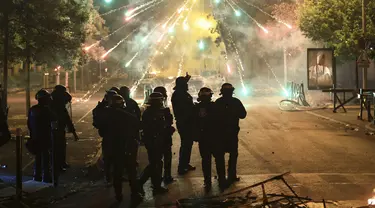 Polisi berdiri di tengah petasan pada malam ketiga protes yang dipicu oleh penembakan fatal polisi terhadap seorang pengemudi berusia 17 tahun di pinggiran Paris Nanterre, Prancis, Jumat, 30 Juni 2023. (AP Photo/Aurelien Morissard)