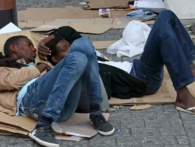 Dua orang imigran berbaring menggunakan kardus bekas sebagai alas di sebuah kamp darurat di jalanan Kota Paris, Prancis, Selasa (6/9). Para imigran berkulit hitam tersebut hidup terlantar di pinggir jalan kota tersebut. (REUTERS/Benoit Tessier)