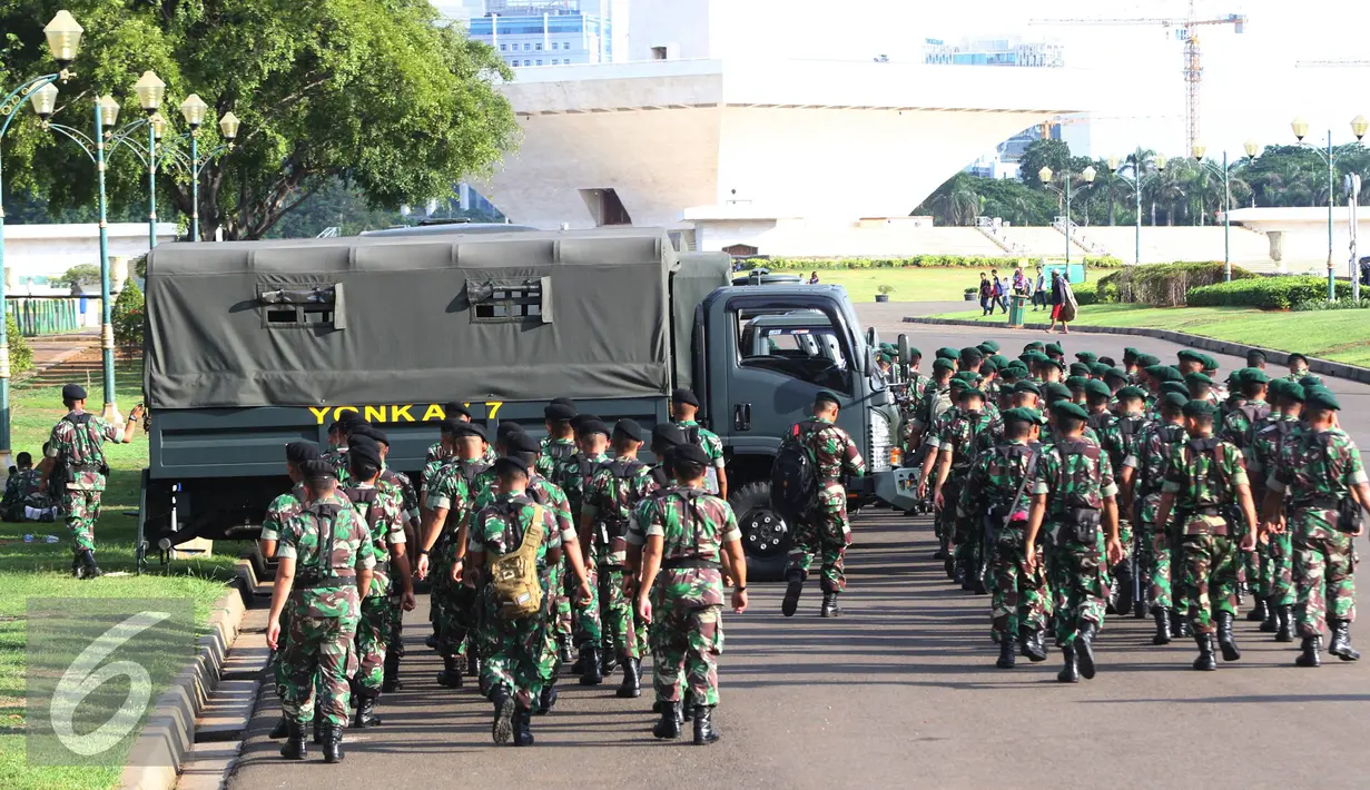 Petugas TNI bersiap untuk mengikuti apel gabungan di Monas, Jakarta, Kamis (31/12). Sebanyak 1300 personel gabungan yang terdiri dari polisi, TNI, Pol PP, dan Pramuka dikerahkan untuk mengamankan perayaan malam tahun baru. (Liputan6.com/Immanuel Antonius)