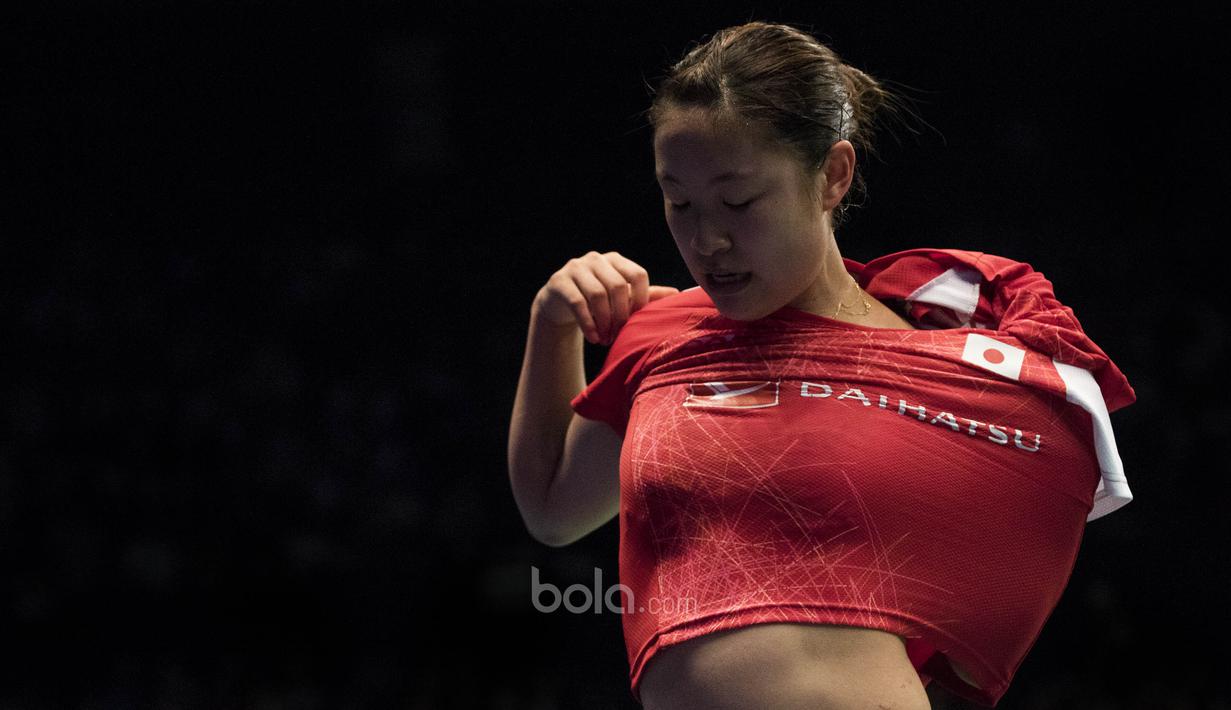 Karena terbiasa, Nozomi Okuhara, sudah tidak kesulitan ganti baju di pinggir lapangan. (Bola.com/Vitalis Yogi Trisna)