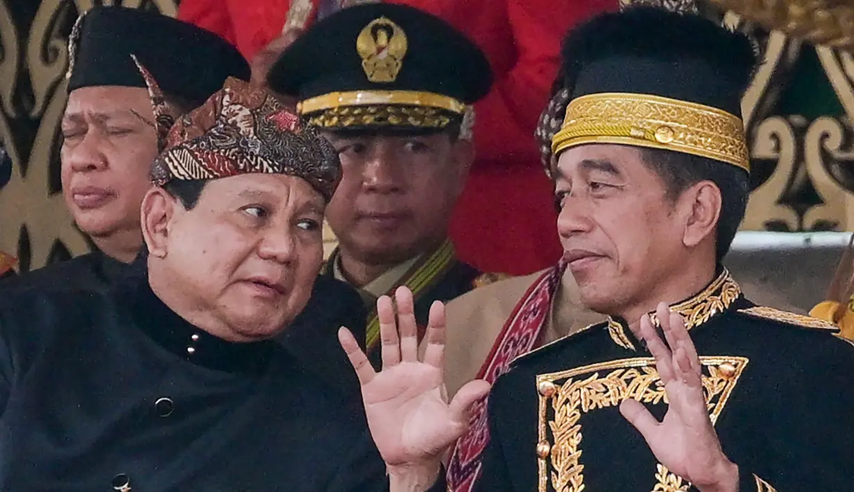 Upacara tersebut menjadi yang pertama diadakan di IKN, sekaligus menjadi terakhir Presiden ke-7 Joko Widodo sebelum menyerahkan tampuk kepemimpinan kepada Presiden Prabowo. Tampak dalam foto, Presiden Indonesia Joko Widodo berbicara dengan Presiden terpilih Prabowo Subianto (kiri) setelah upacara pengibaran bendera yang menandai Hari Kemerdekaan ke-79 Indonesia di Istana Kepresidenan di Ibu Kota Nusantara, Sepaku, Penajam Paser Utara, Kalimantan Timur, pada 17 Agustus 2024. (BAY ISMOYO/AFP)